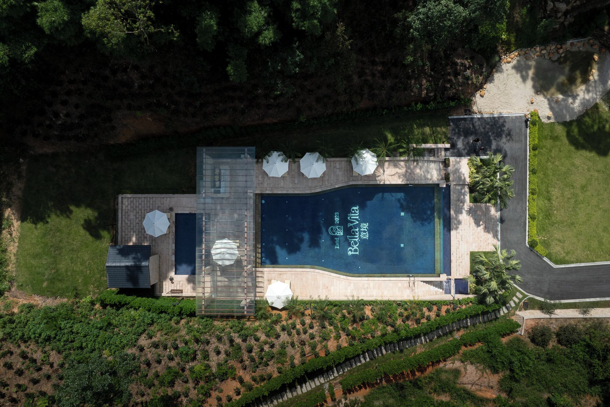 Vista aérea de um resort com piscina, área coberta e jardins bem cuidados.