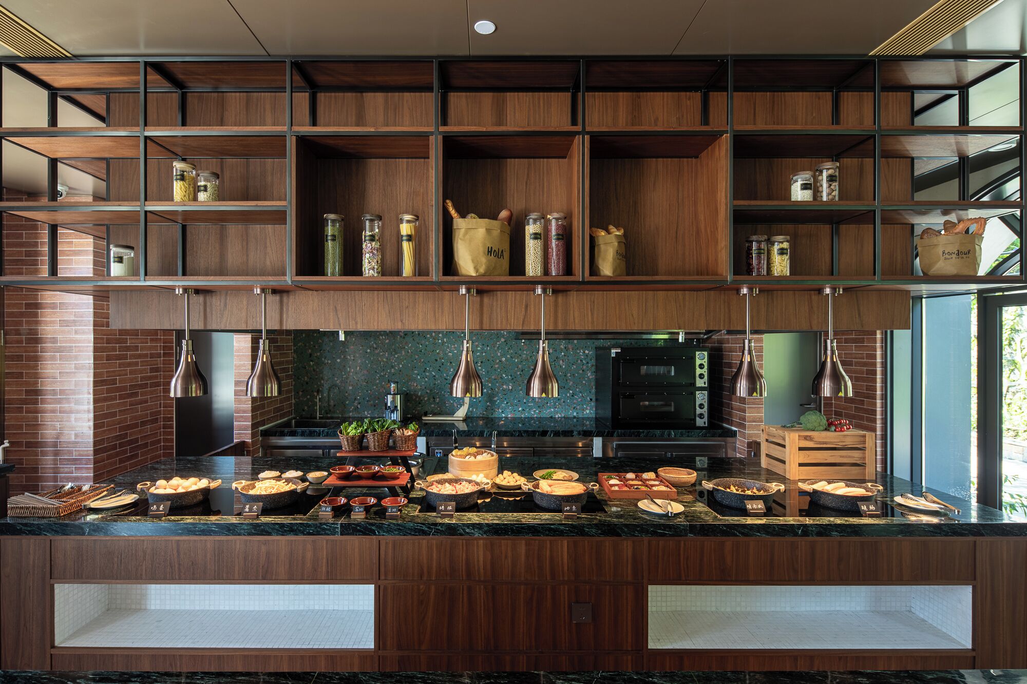 A modern kitchen with wooden shelves, a marble countertop, and various food items displayed.