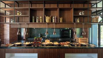 A modern kitchen with wooden shelves, a marble countertop, and various food items displayed.