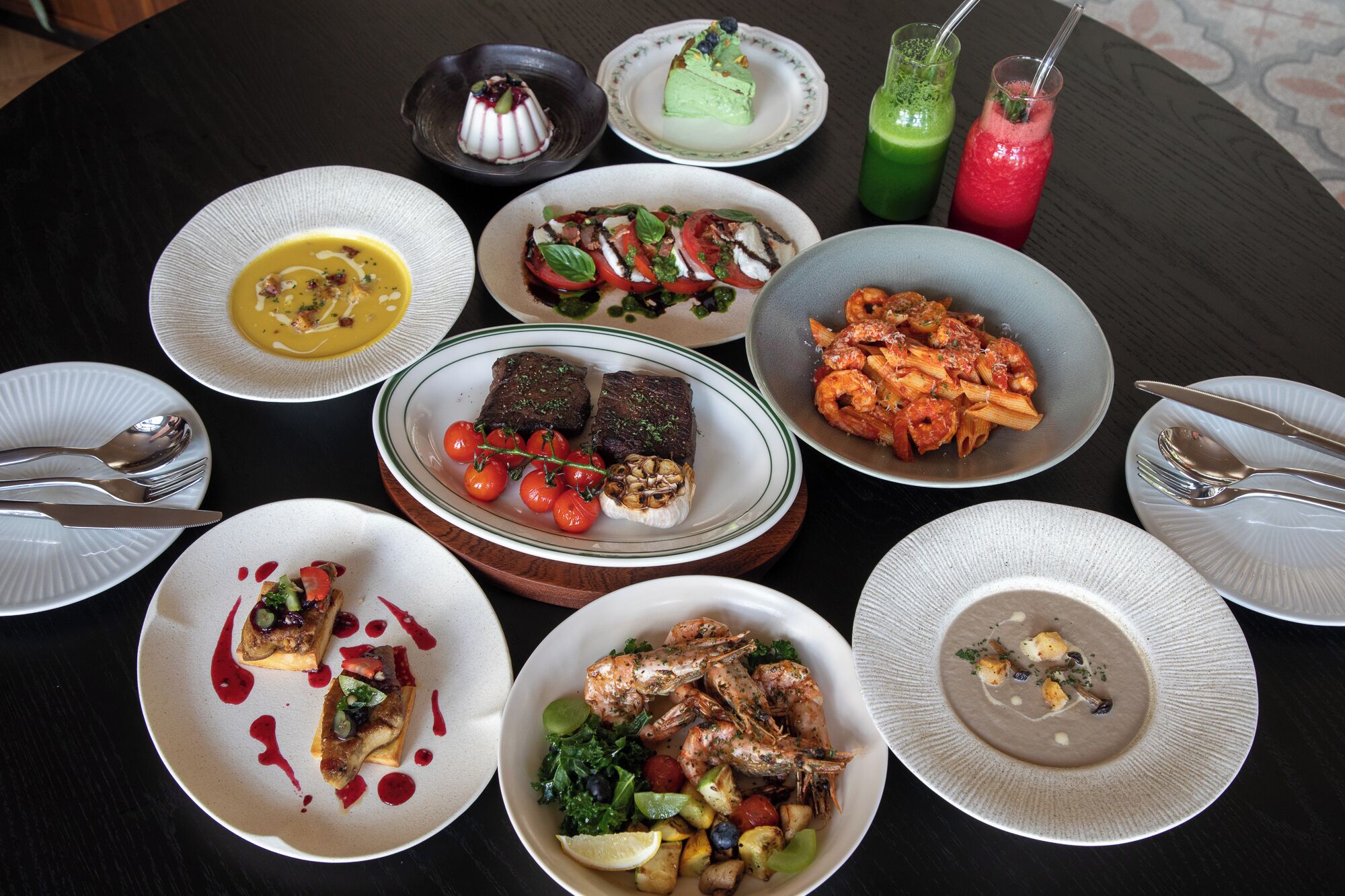 A variety of dishes on a round table, including seafood, pasta, and salads.