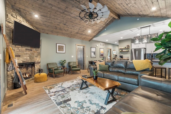 A spacious living room with a fireplace, leather sofa, and a large plant. - Lake Lodge w/ Boat Slip, Game Room & Free Family Tickets! (Branson)