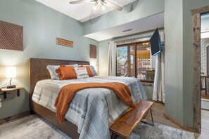 A bedroom with a bed, a bedside table, a bench, a ceiling fan, and a window with curtains. - Lake Lodge w/ Boat Slip, Game Room & Free Family Tickets! (Branson)