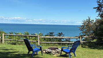 Two blue chairs facing a wooden fence overlooking a body of water.