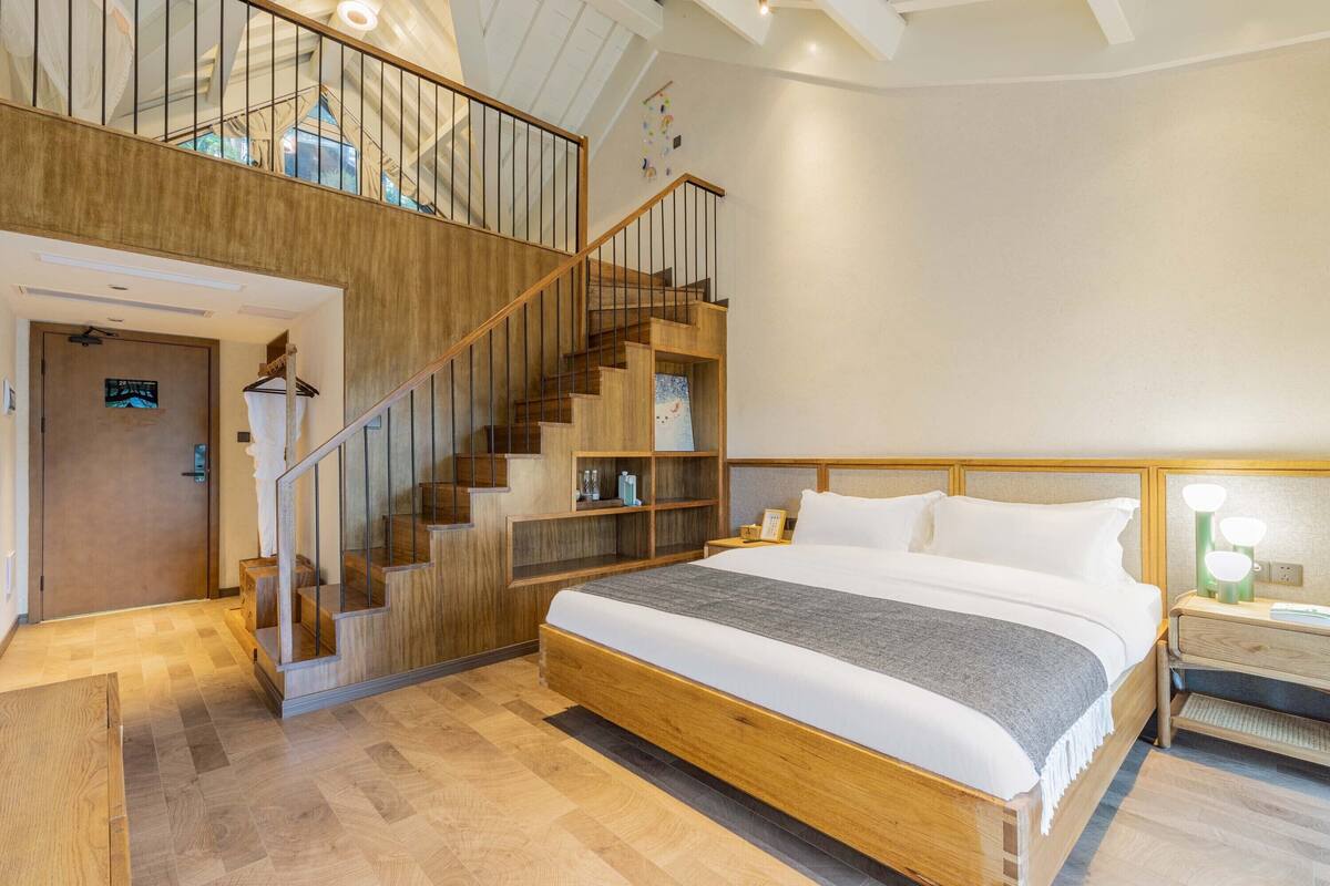 Un dormitorio espacioso con una cama grande, una escalera de madera y estantes empotrados.