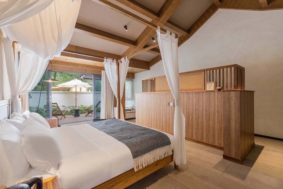 Un dormitorio con una cama grande, cabecera de madera y vistas al exterior.
