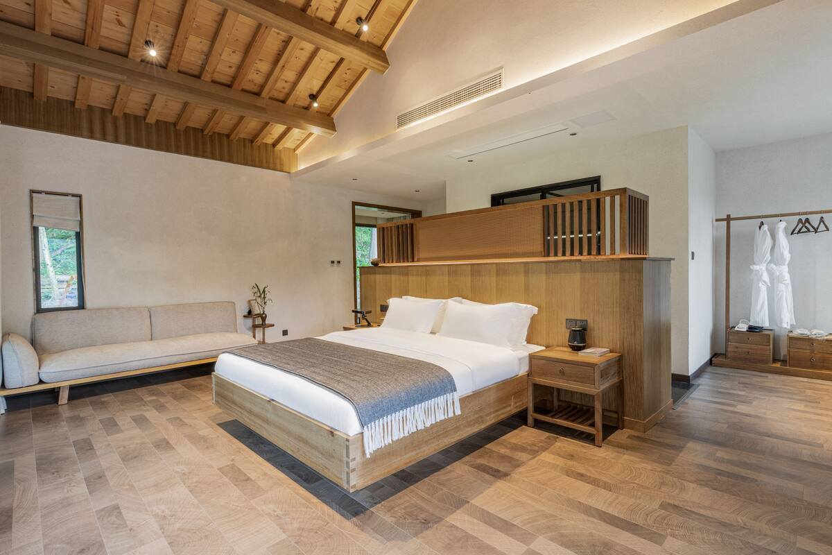 Un dormitorio moderno con una cama grande, cabecera de madera y un banco empotrado.