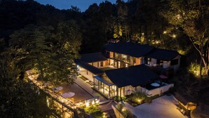 A modern house with multiple levels, large windows, and a well-lit outdoor area. - Qingcheng Mountain Jiuxipo (Chengdu)
