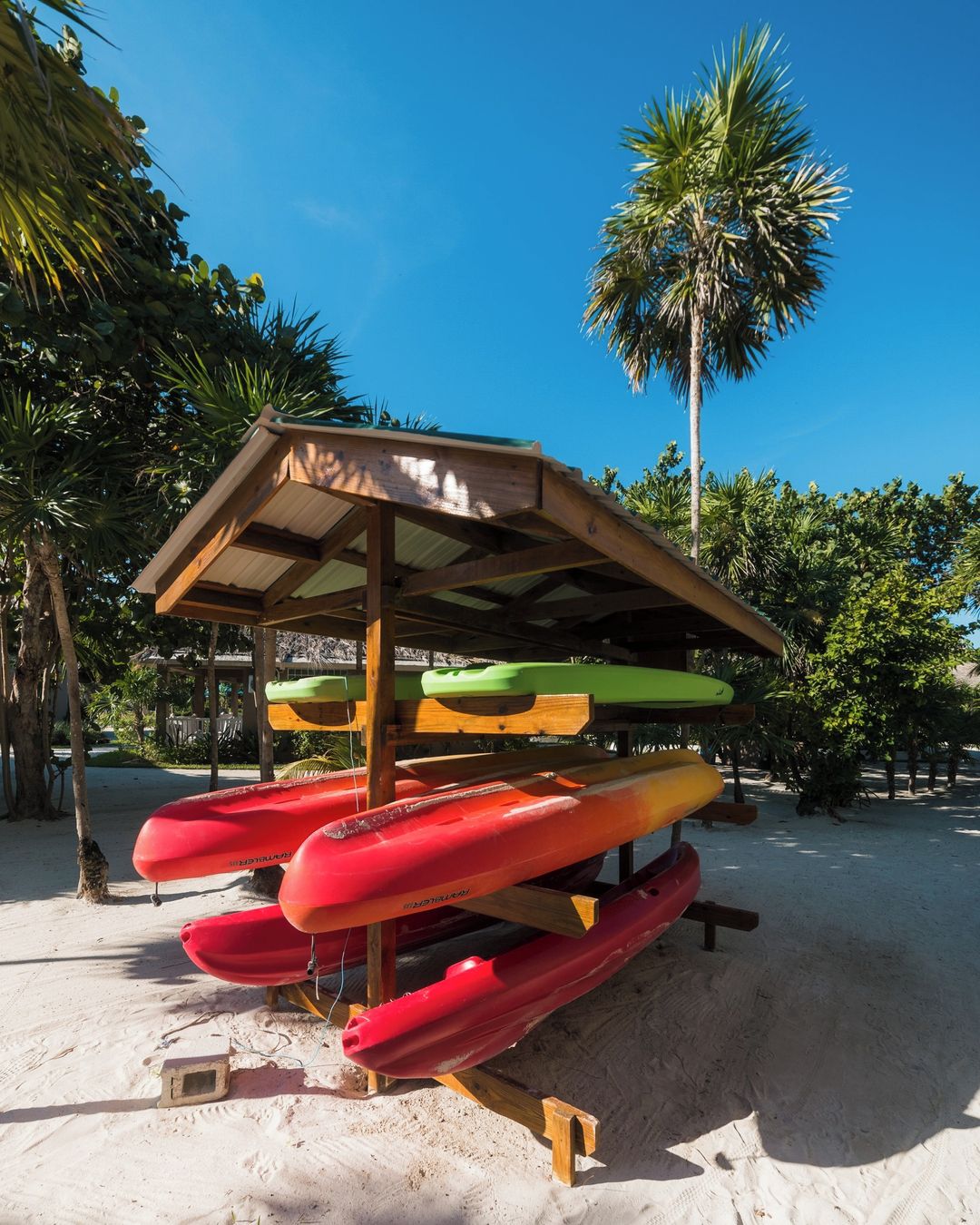 Zona techada para guardar kayaks, con varios kayaks de diferentes colores.