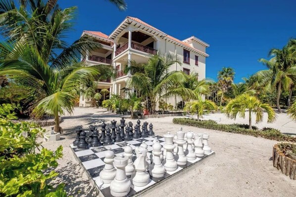 A large outdoor chessboard set up in a resort area with a building in the background.