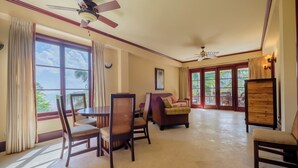 A spacious living area with a dining table, chairs, a sofa, and a ceiling fan. - Tropical Tranquility Suite | Upper Level 1BR Sea (San Pedro)