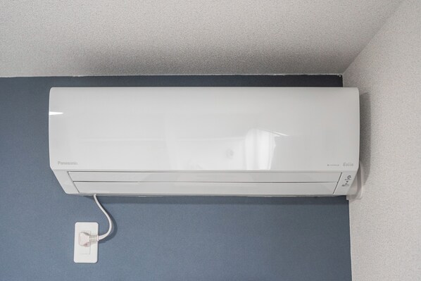 Un aire acondicionado blanco de Panasonic montado en una pared azul.