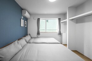 Un dormitorio con dos camas, una ventana con cortinas, un armario y un aire acondicionado instalado en la pared.