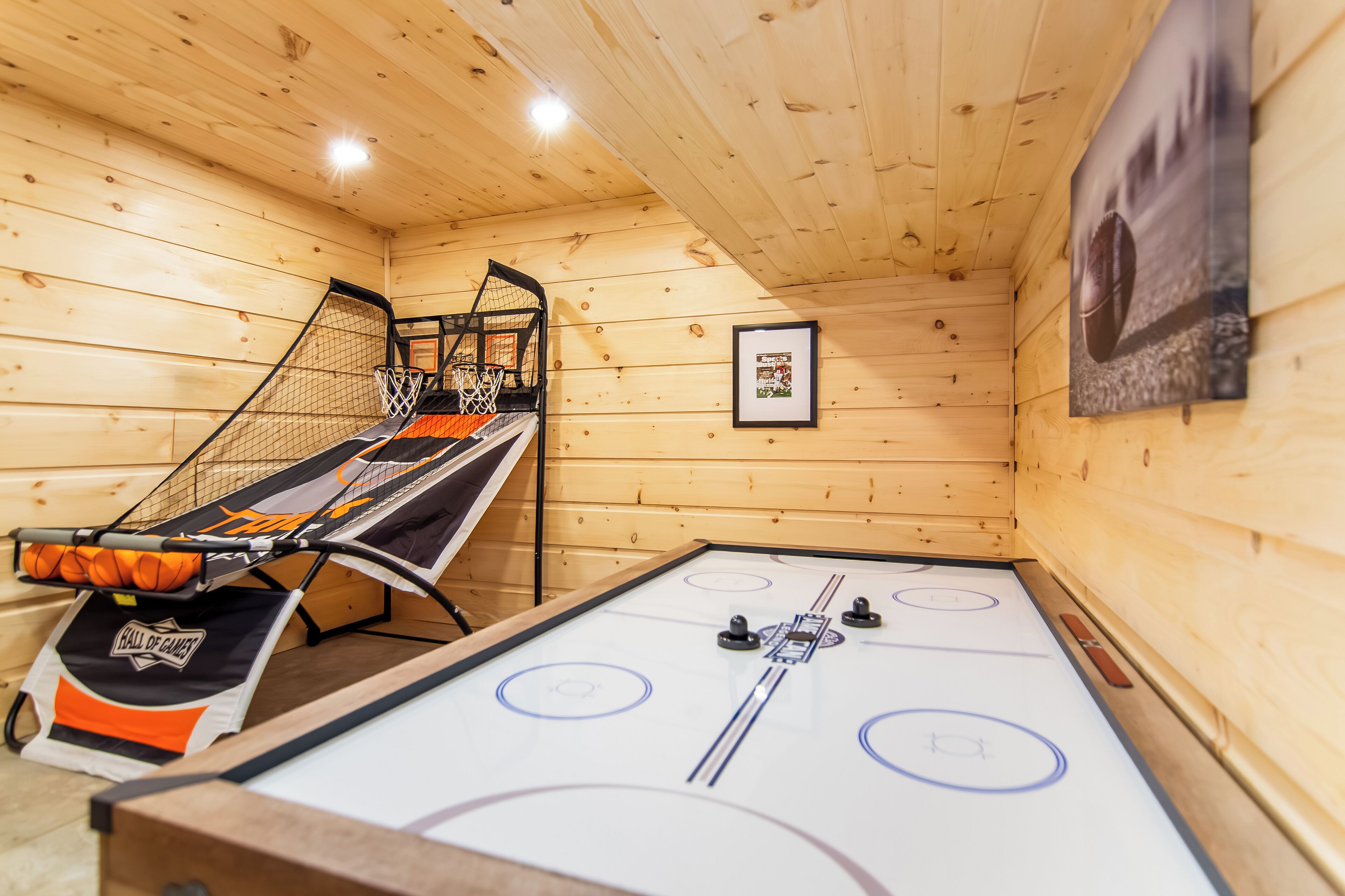 Um quarto com piso de madeira, mesa de pebolim e cesta de basquete.