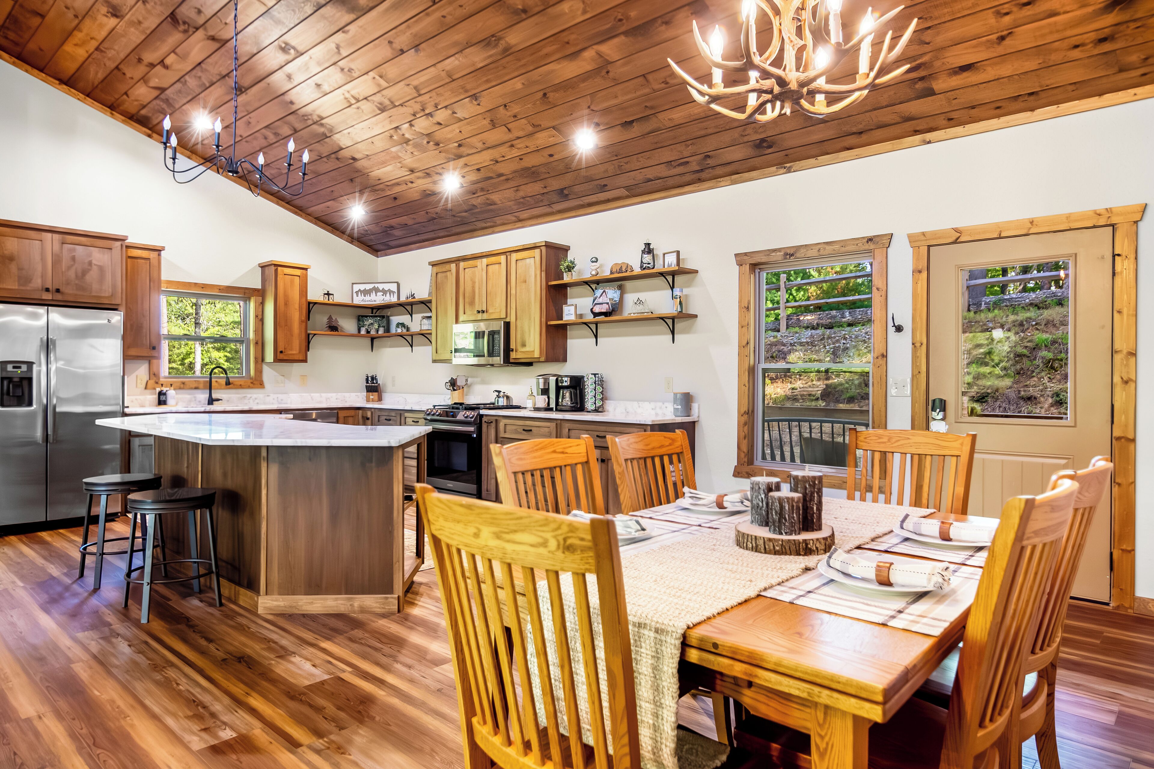 A kitchen with wooden cabinets, a central island, and a dining area with wooden chairs and a table.