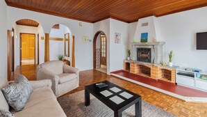 Un salón con chimenea, techo de madera y un sofá.