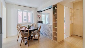 Une cuisine moderne dotée d’un plan de travail en marbre, de chaises en bois et d’une bibliothèque intégrée.