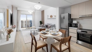 A modern kitchen with a dining area, a built-in oven, and a large window offering a city view. - Maison Privee - Sleek Yas Getaway w/ Ferrari World and Canal Views (Abu Dhabi)