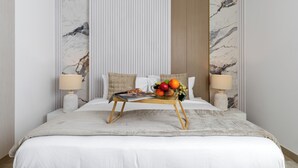 A neatly made bed with a fruit bowl, two bedside lamps, and a magazine on a wooden table. - Maison Privee - Sleek Yas Getaway w/ Ferrari World and Canal Views (Abu Dhabi)
