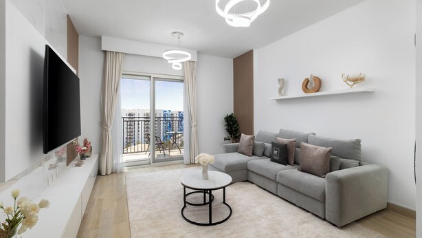 A modern living room with a grey sofa, a round coffee table, and a flat-screen TV mounted on the wall. - Maison Privee - Sleek Yas Getaway w/ Ferrari World and Canal Views (Abu Dhabi)