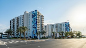 A modern multi-story hotel with balconies, located at a street intersection. - Maison Privee - Sleek Yas Getaway w/ Ferrari World and Canal Views (Abu Dhabi)