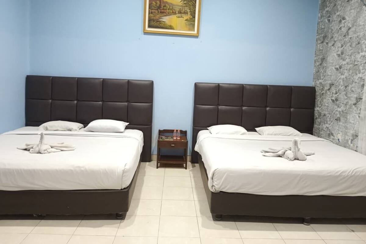 A hotel room with two beds, a nightstand, and a painting on the wall.