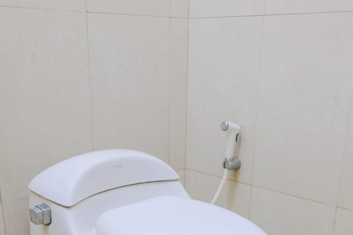 Un inodoro blanco en un baño con paredes y suelo de baldosas.