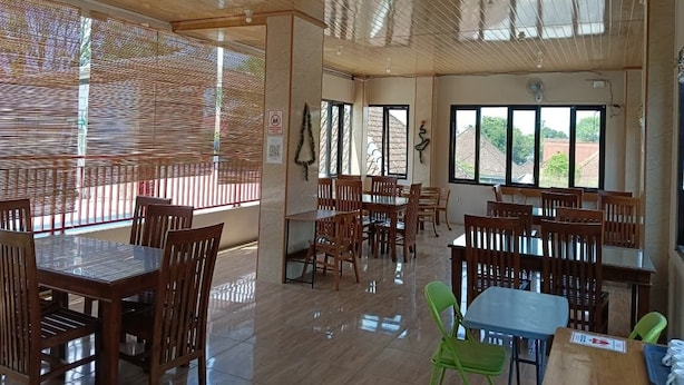 Un vaste espace dédié à la salle à manger, avec des tables et des chaises en bois, de grandes fenêtres et un plafond orné de lambris en bois.