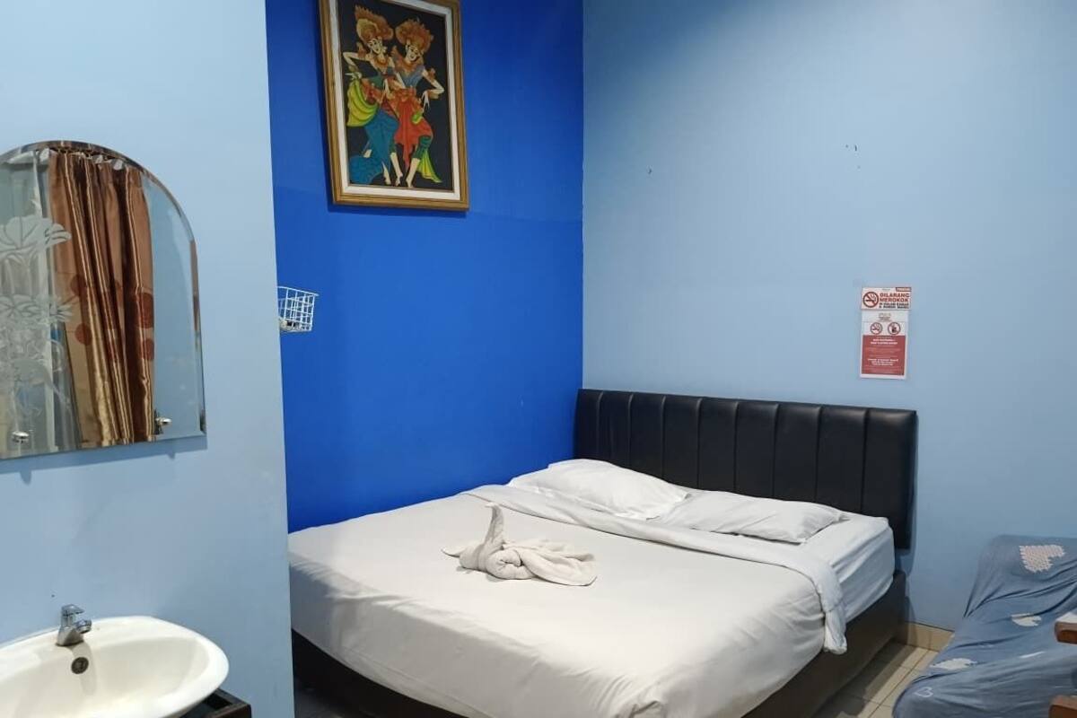 A hotel room with a bed, a sink, and a blue wall.
