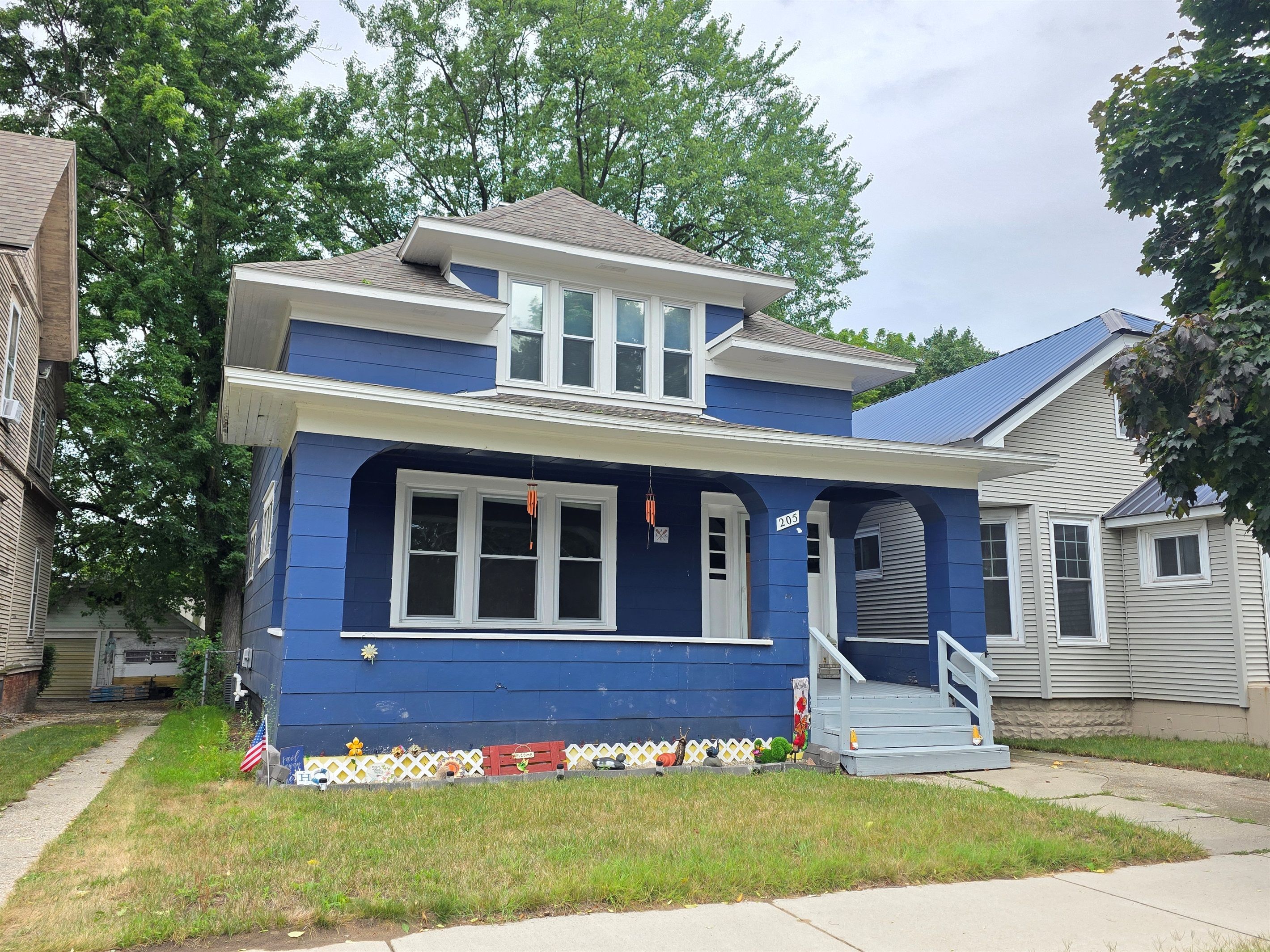 A two-story house with a blue exterior and white trim, a front porch, and a small staircase leading to the entrance.