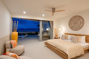 A modern bedroom with a large bed, a ceiling fan, and a view of a mountainous landscape through a sliding glass door. - Bow Villa by Sublime Samui Villas (Koh Samui)