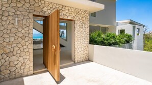 A modern building with a stone facade, a wooden door, and a view of the sea.