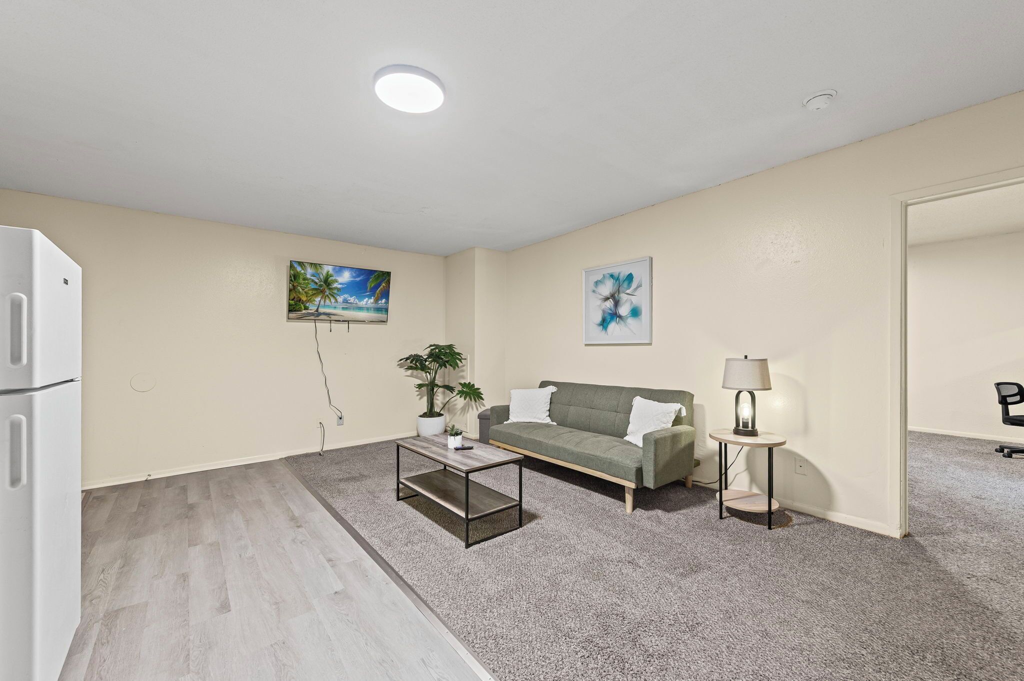 Ein Wohnzimmer mit Sofa, Couchtisch, Lampe und einer Zimmerpflanze.