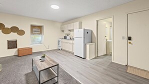 Kompakti asuintila, jossa on pieni keittiö, ruokailutila ja ovi, joka johtaa toiseen huoneeseen.