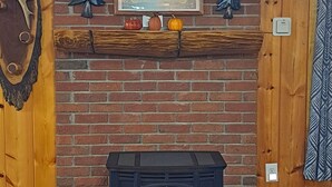 Une cheminée avec un mur en briques, un lambris en bois et une étagère ornée d’objets décoratifs.