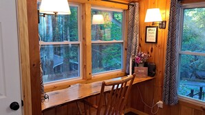 Une cabane en bois avec un banc et deux fenêtres, chacune équipée d’une lampe.