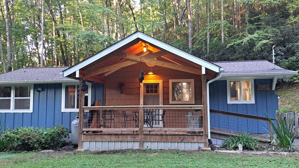 Une cabane dotée d’un porche, d’une petite terrasse et d’une façade en bois.