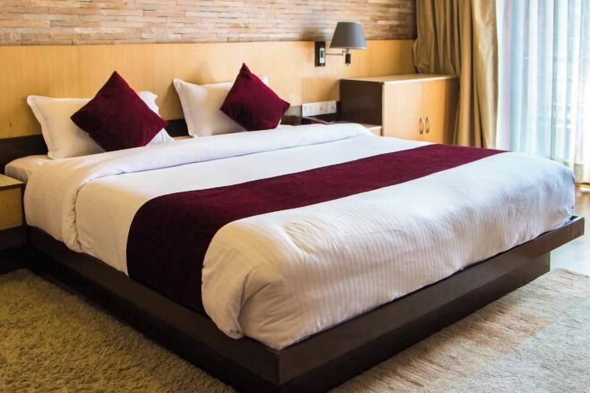 A modern hotel room with a large bed, dark wooden headboard, and a neutral color scheme.