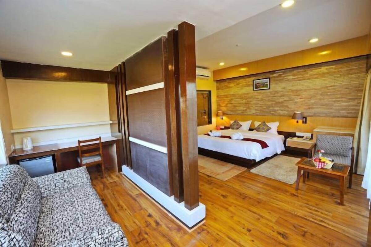 A hotel room with a bed, a desk, a chair, and a sofa.