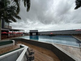 Piscina con muelle de madera, sillas de descanso y sombrillas.