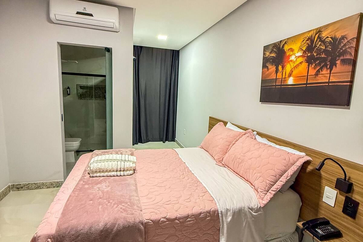 Une chambre à coucher avec un lit, un tableau, une table de chevet et une porte de salle de bain.
