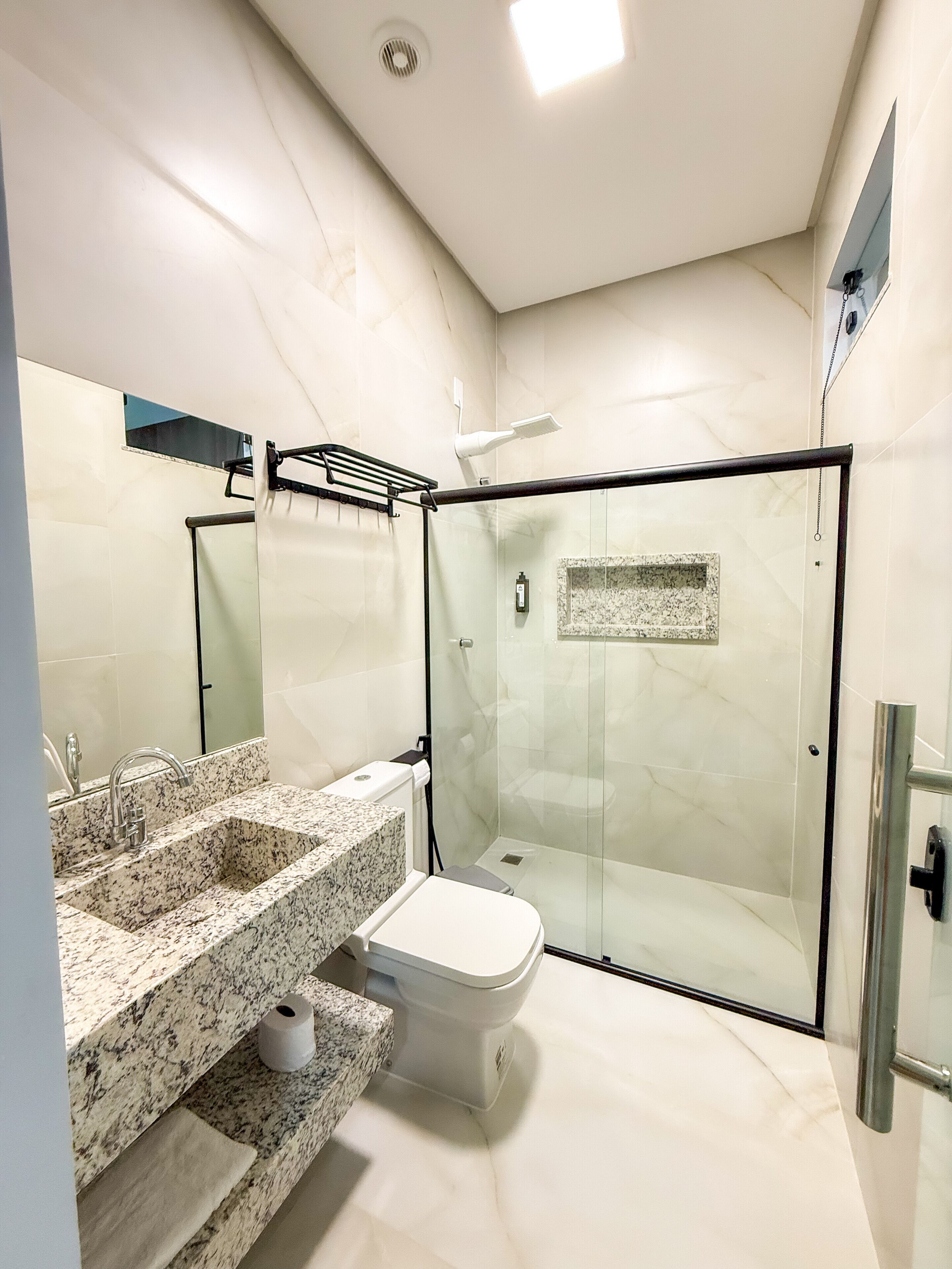 A modern bathroom with a glass-enclosed shower, a marble sink, and a toilet.