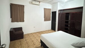 A small, clean room with a bed, a sofa, and a wardrobe.