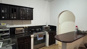 A compact kitchen with dark cabinets, a stove, a microwave, and a sink.
