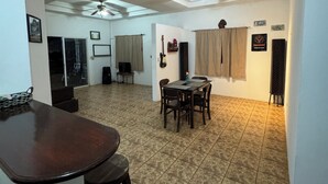 A spacious living area with a dining table and chairs, a bar area, and ceiling fans.