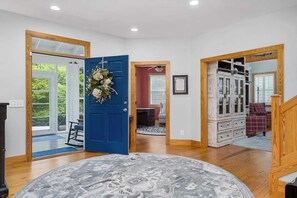 Un recibidor amplio con una puerta azul, una alfombra y una escalera que conduce a una habitación con un armario.