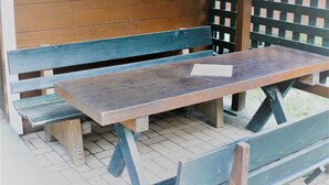 A wooden picnic table with benches, set on a tiled patio. - Gujohachimanshizenen - Bungalow (Gujo)
