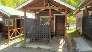 A wooden cabin with a covered porch, a sign indicating room number 204, and a view of a forested mountain in the background. - Gujohachimanshizenen - Bungalow (Gujo)