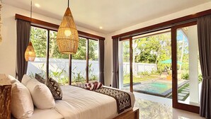 A bedroom with a large bed, a hanging light fixture, and a view of a swimming pool.