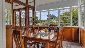 Un comedor con una mesa y sillas de madera, un rompecabezas sobre la mesa y vista a zonas verdes al exterior.