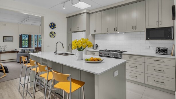 Una cocina moderna con una isla grande, armarios grises y una estufa de acero inoxidable.